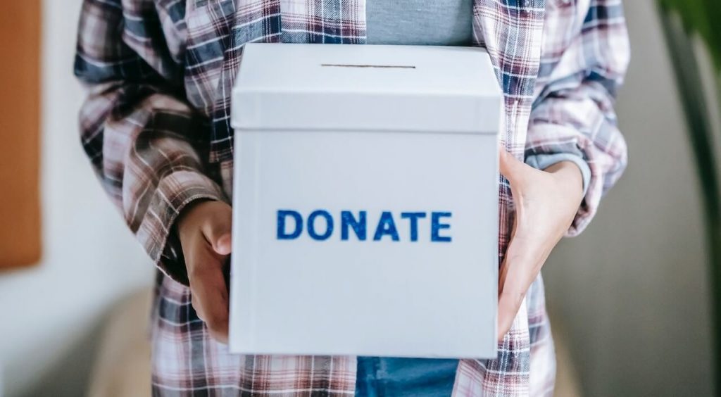 Image of a person holding a box labeled 'Donate,' symbolizing their act of giving and generosity.